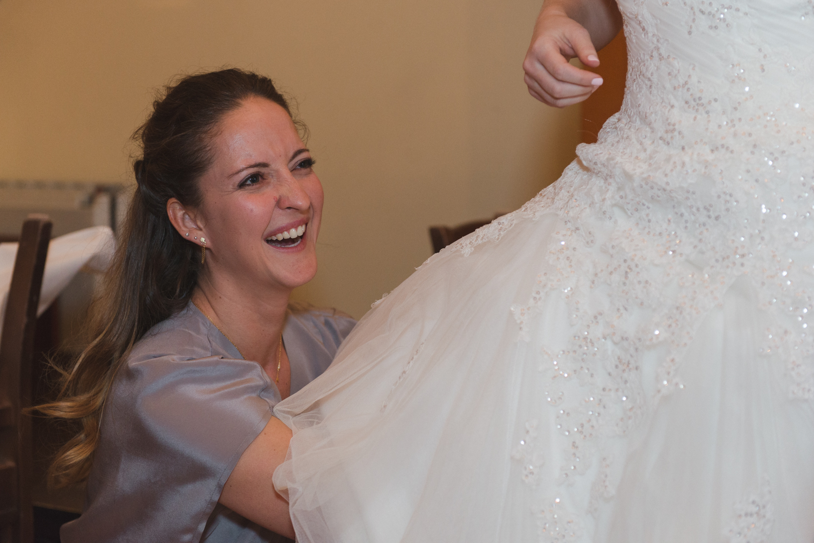 Bridesmaid helping bride put on her wedding dress