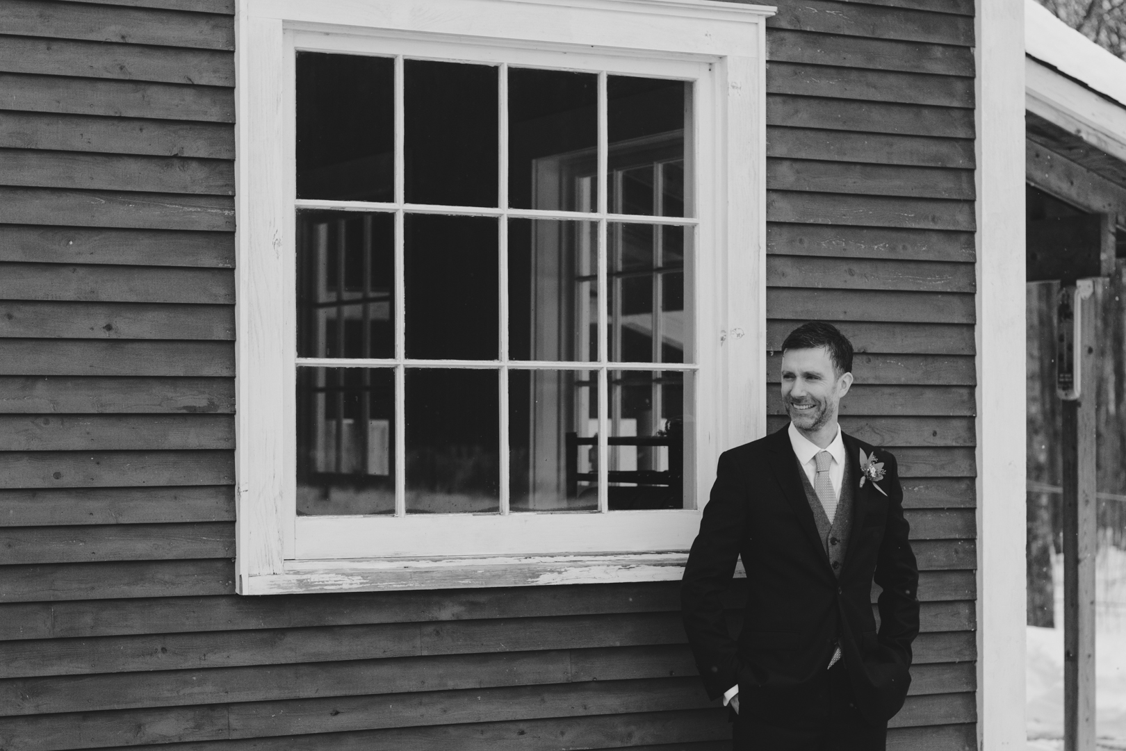 Groom smiling at his bride against old rustic window