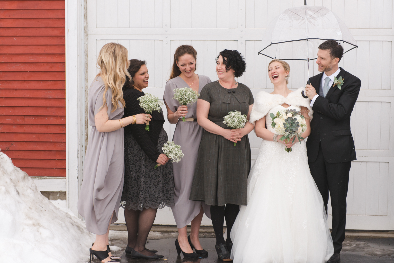 Bride and bridesmaids laughing in front of white door at Temples Sugar Bush