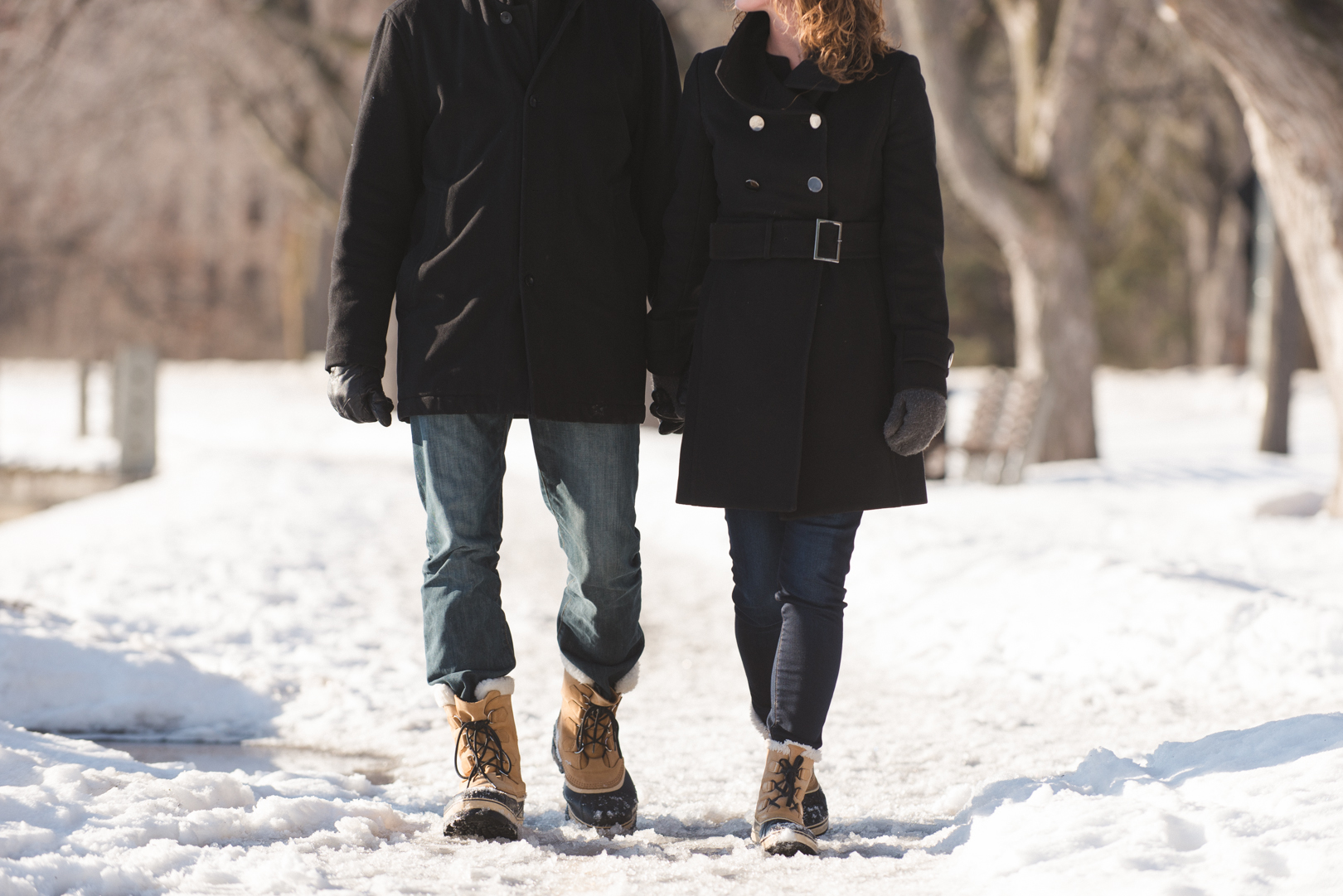 couple walking along a snow covered path with matching Sorel boots