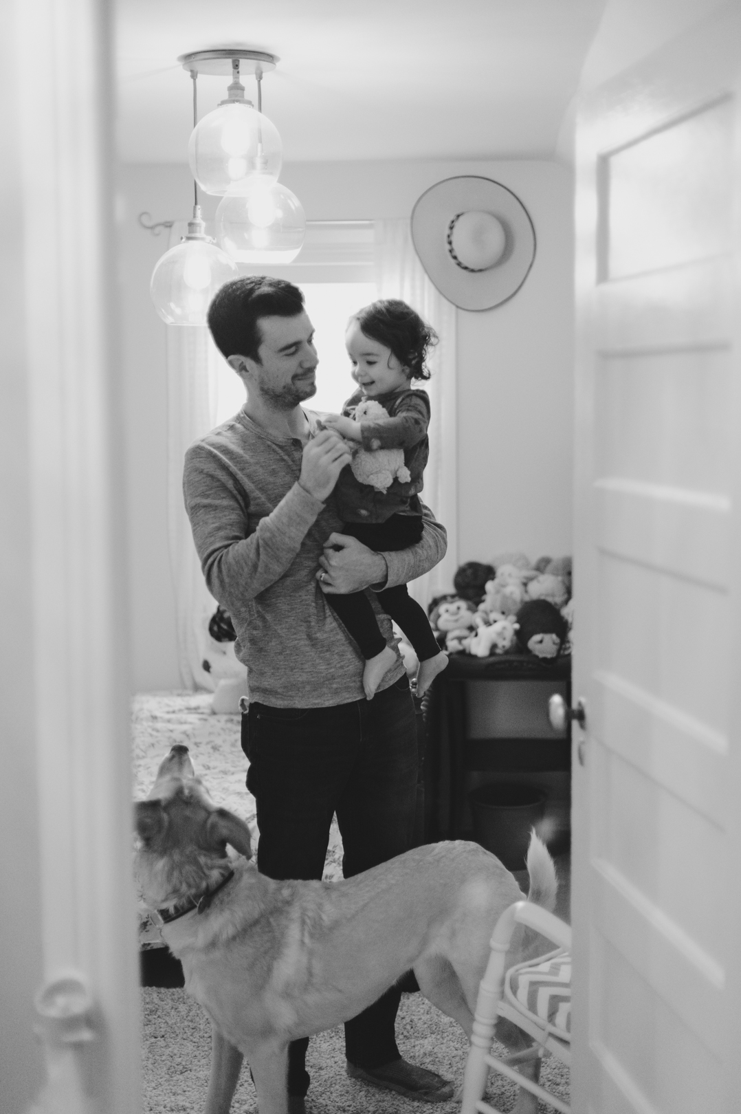 Dad, daughter and dog in child's bedroom on a Saturday morning. Photo by Ashley Notley Photography.