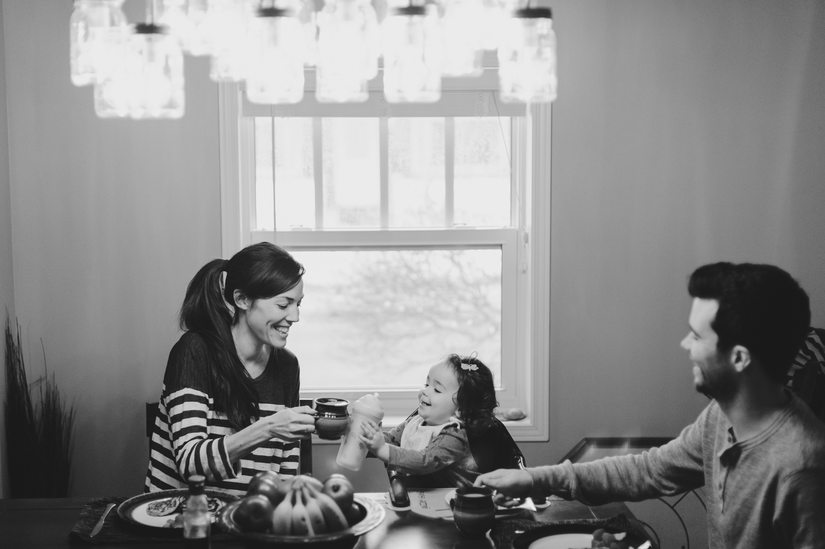 Family cheers during Saturday morning breakfast at the table. Dad and daughter playing together on Saturday morning. Photo by Ashley Notley Photography.