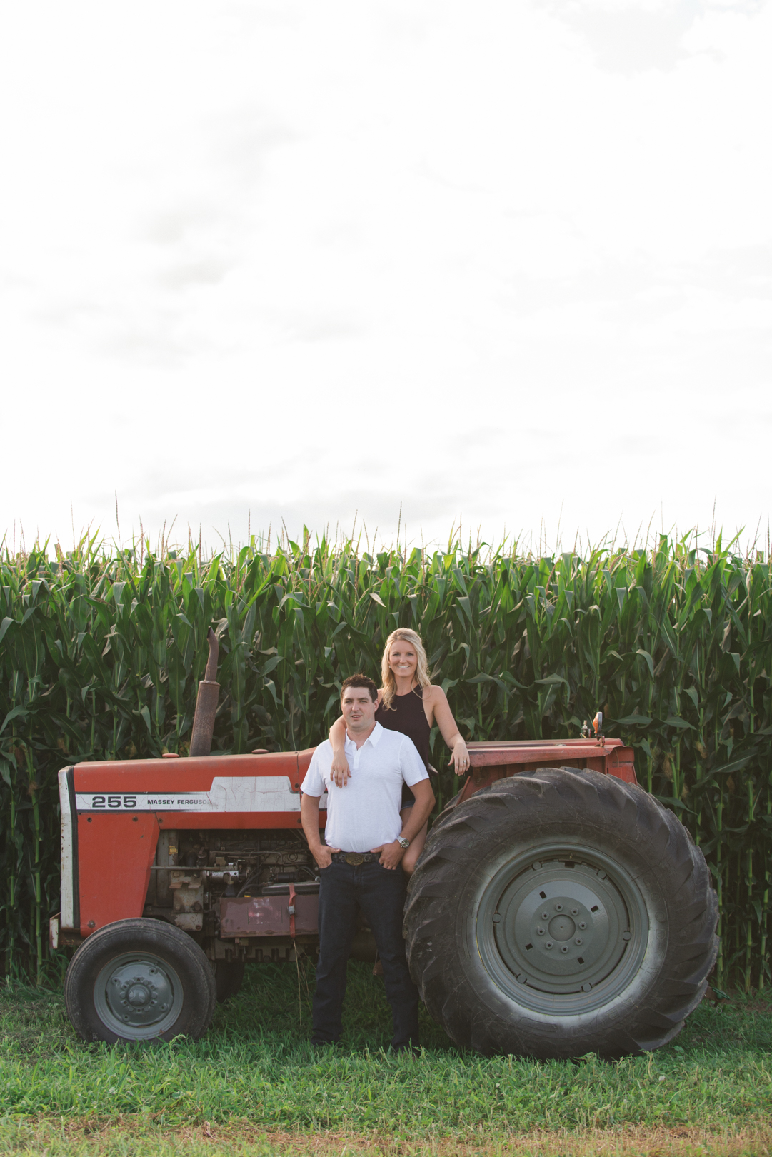 engaged couple kissing next to old tractor