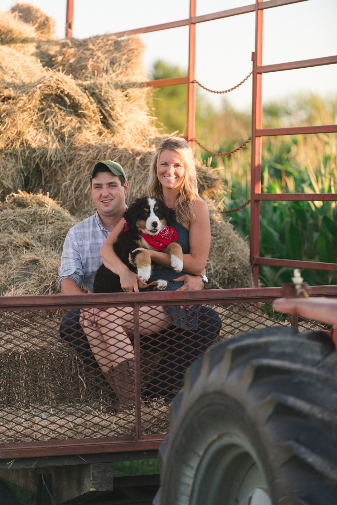 engaged couple with dog in hay wagon