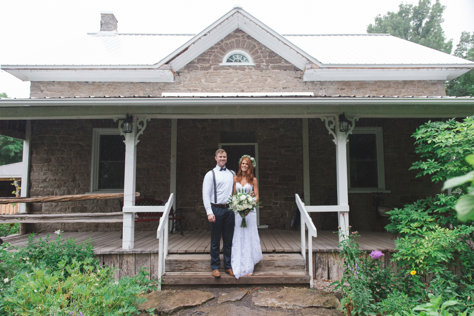 bride and groom on steps of old farm house