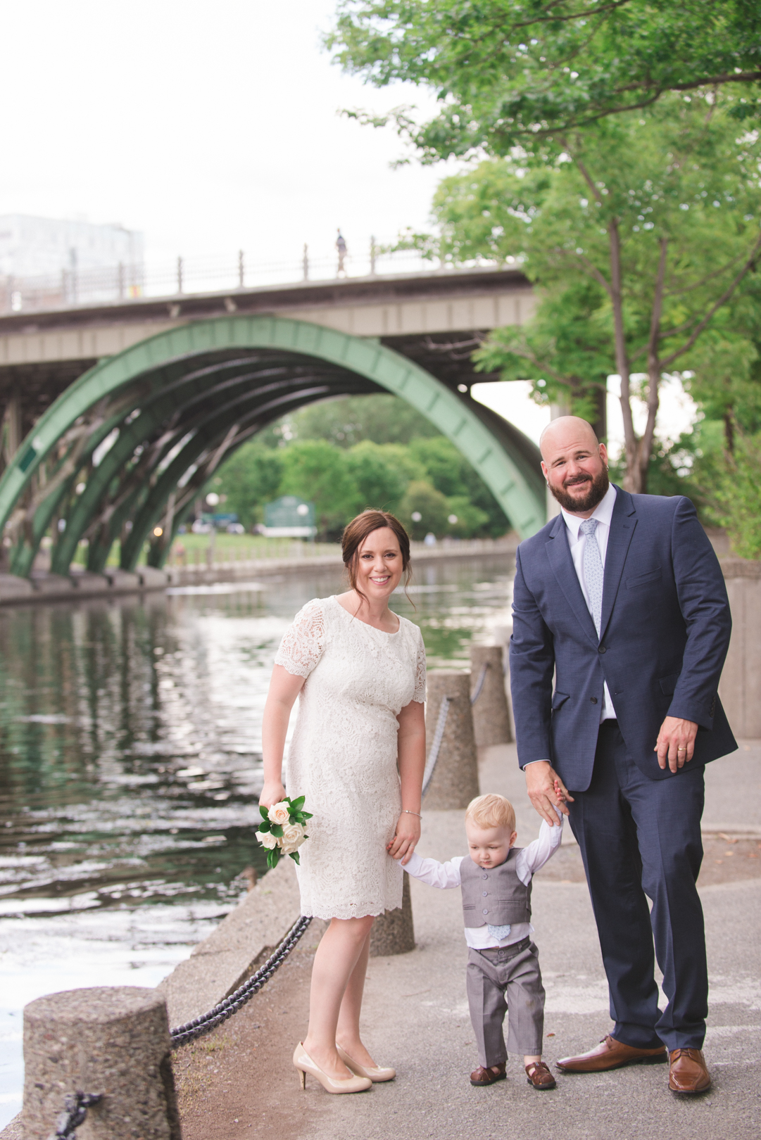 bride and groom with their son by the rideau canal laurier bridge
