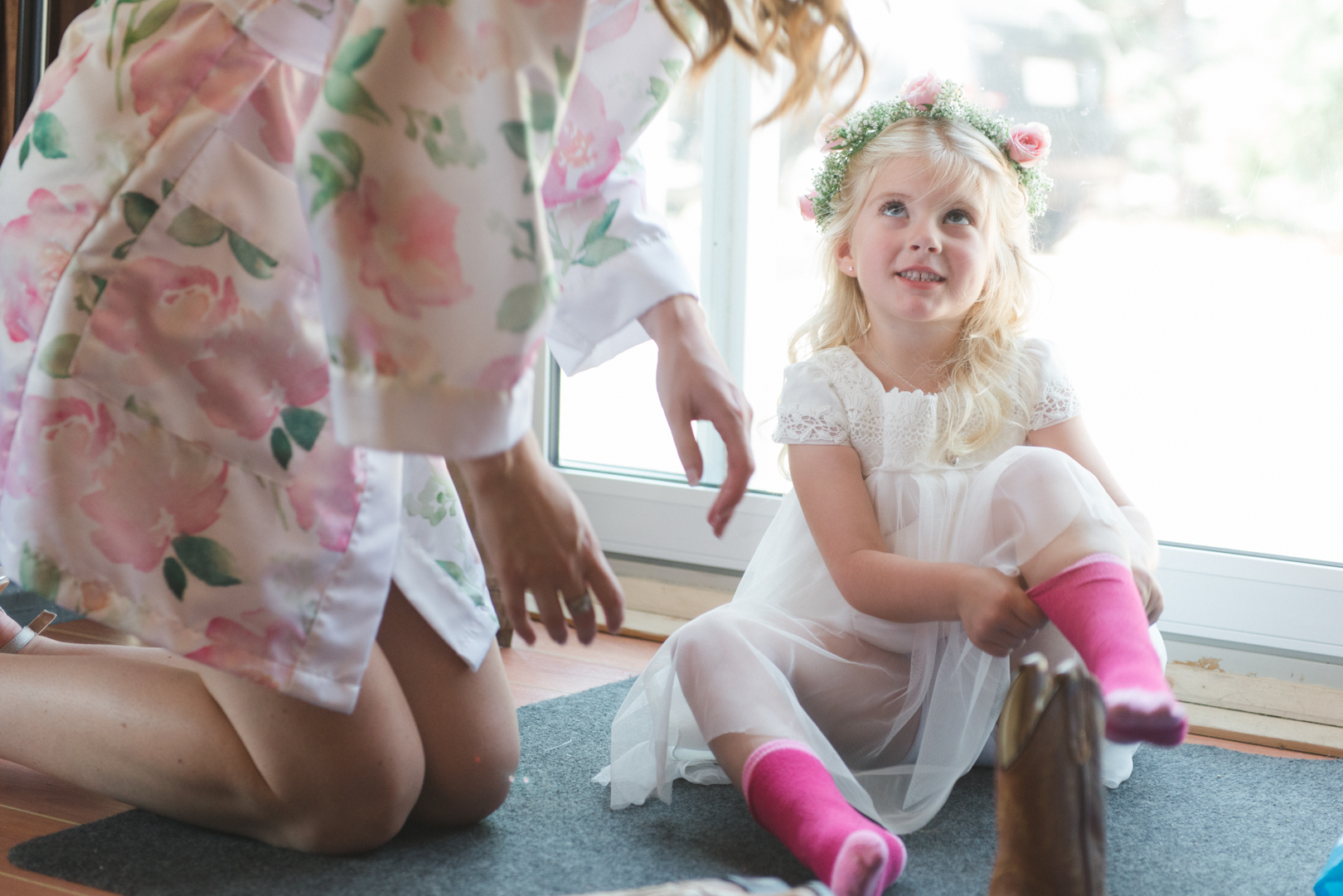 bride helping flower girl put on cowboy boots
