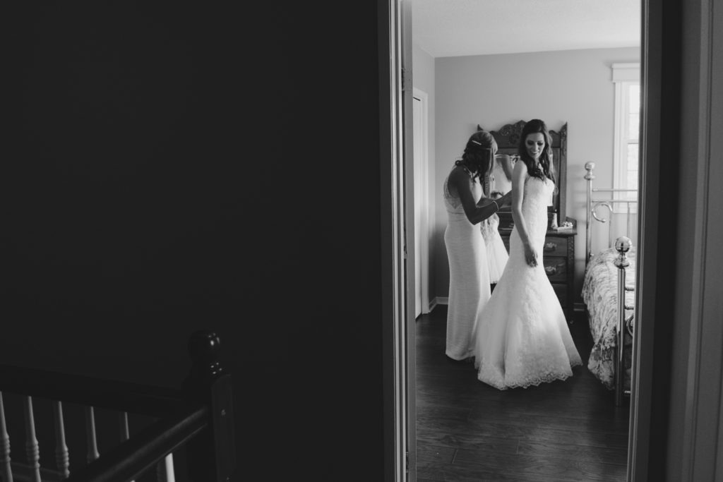 mother of the bride helping bride into her dress
