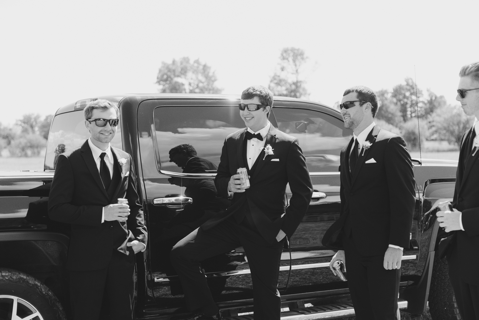 groom and groomsmen drinking beer by pickup truck