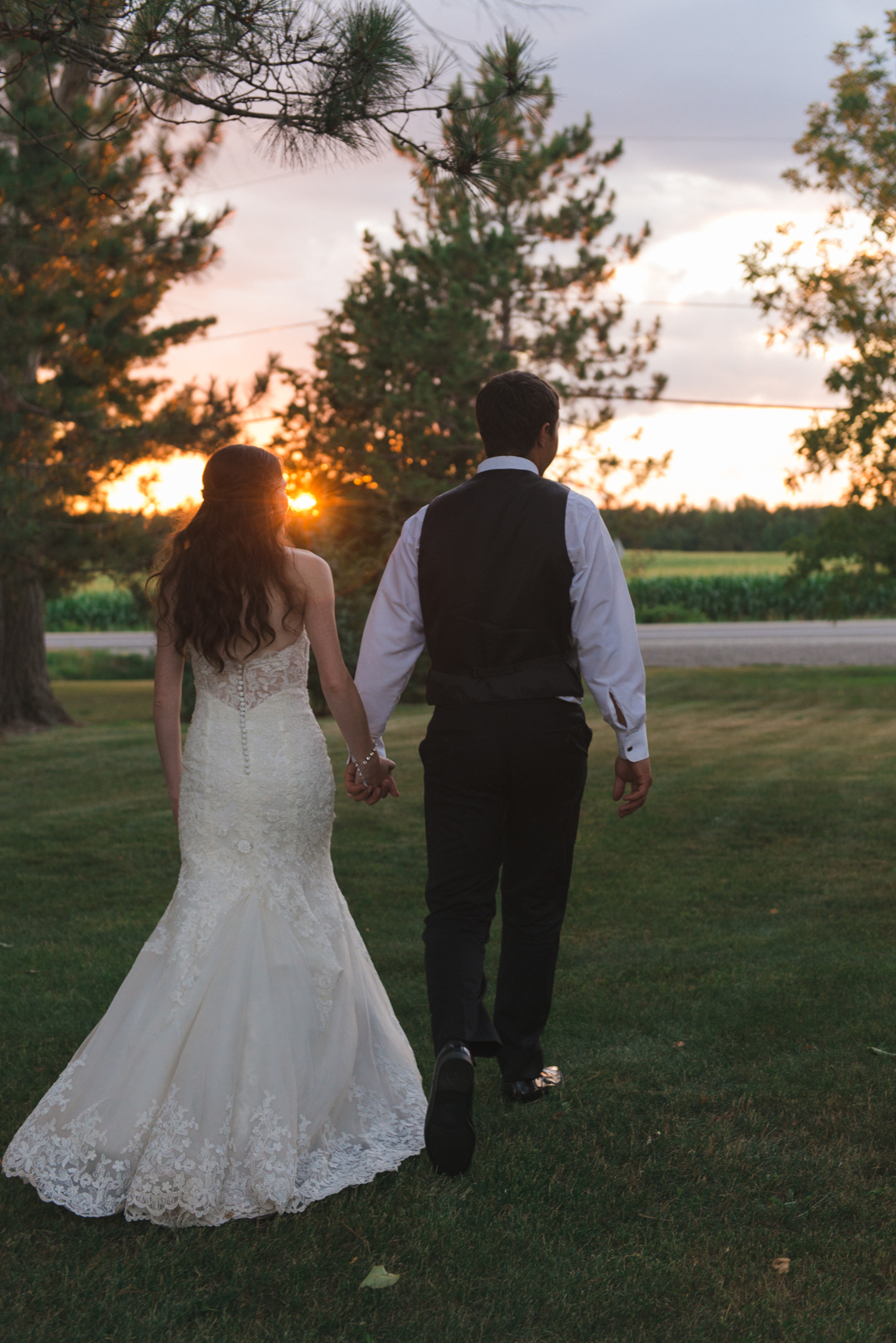 bride and groom walking towards sunset
