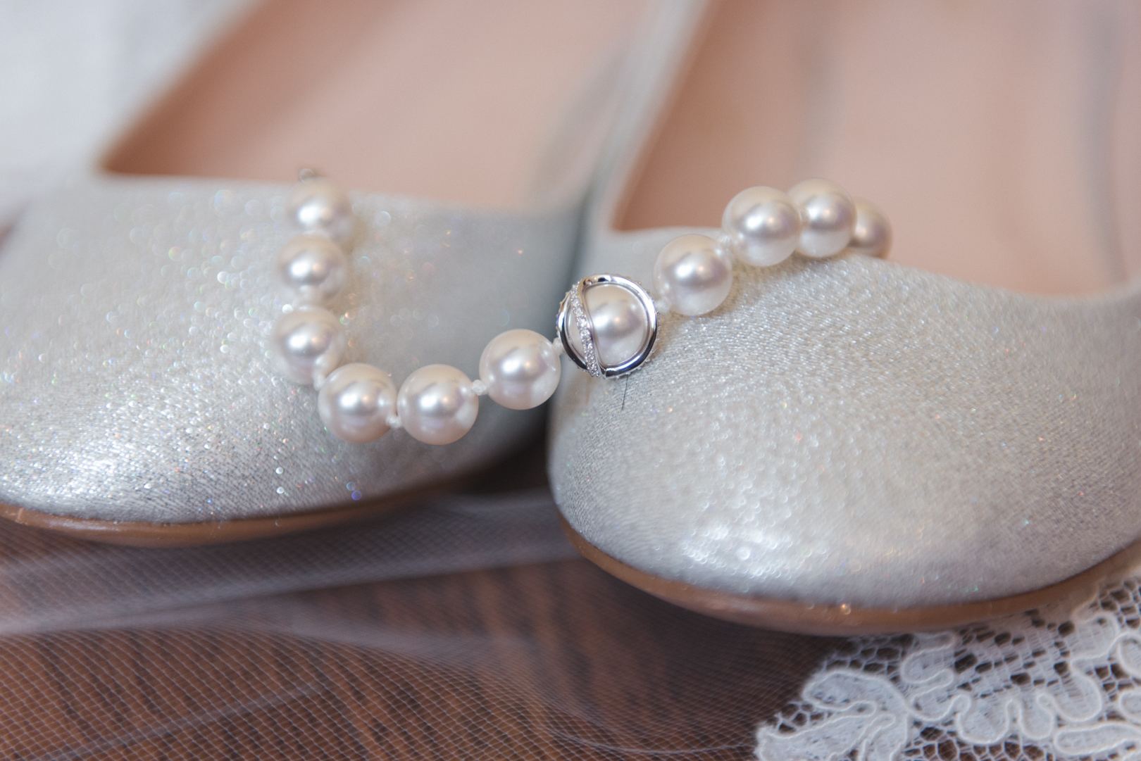 pearl necklace draped over bride's wedding shoes