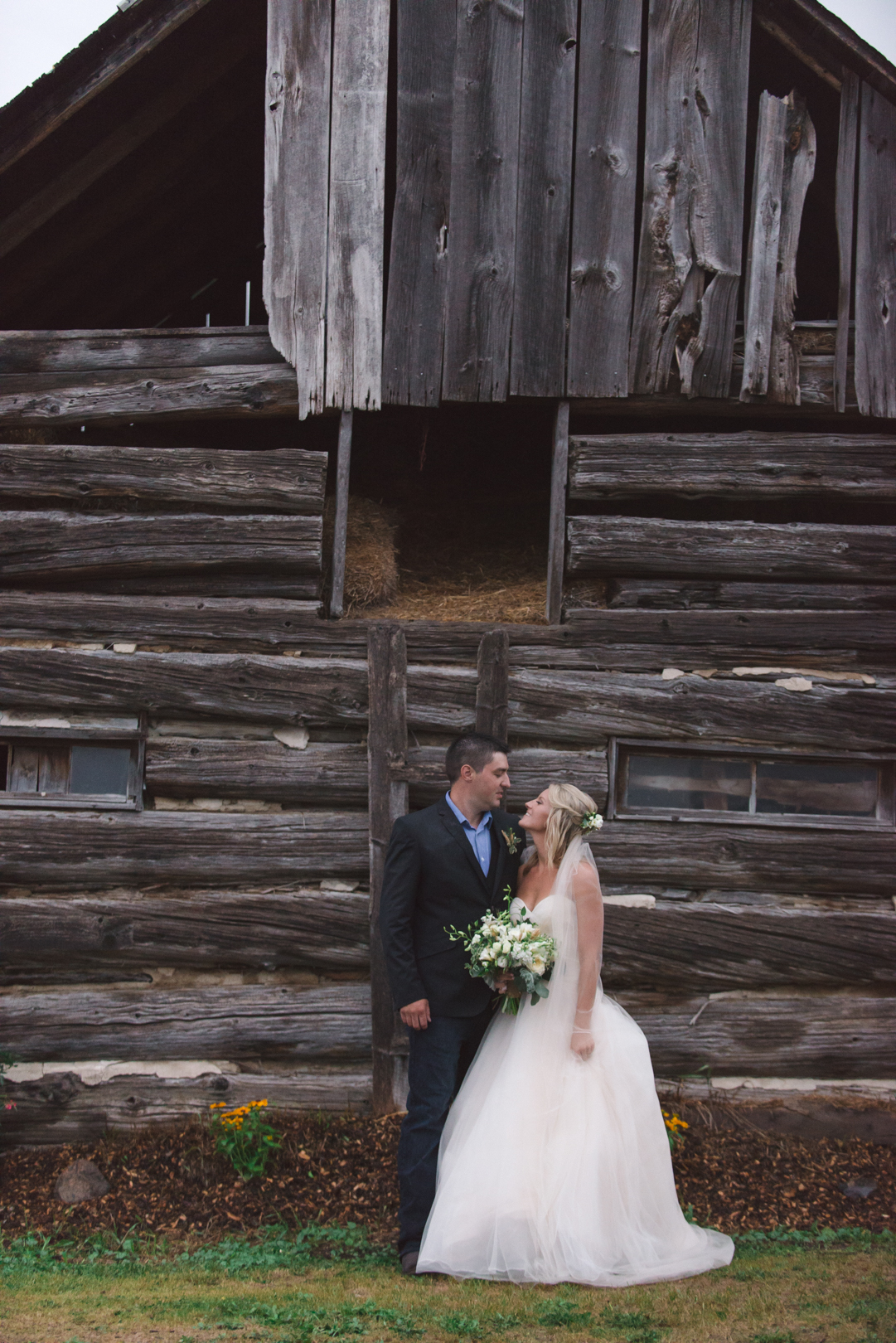bride and groom in front of old barn