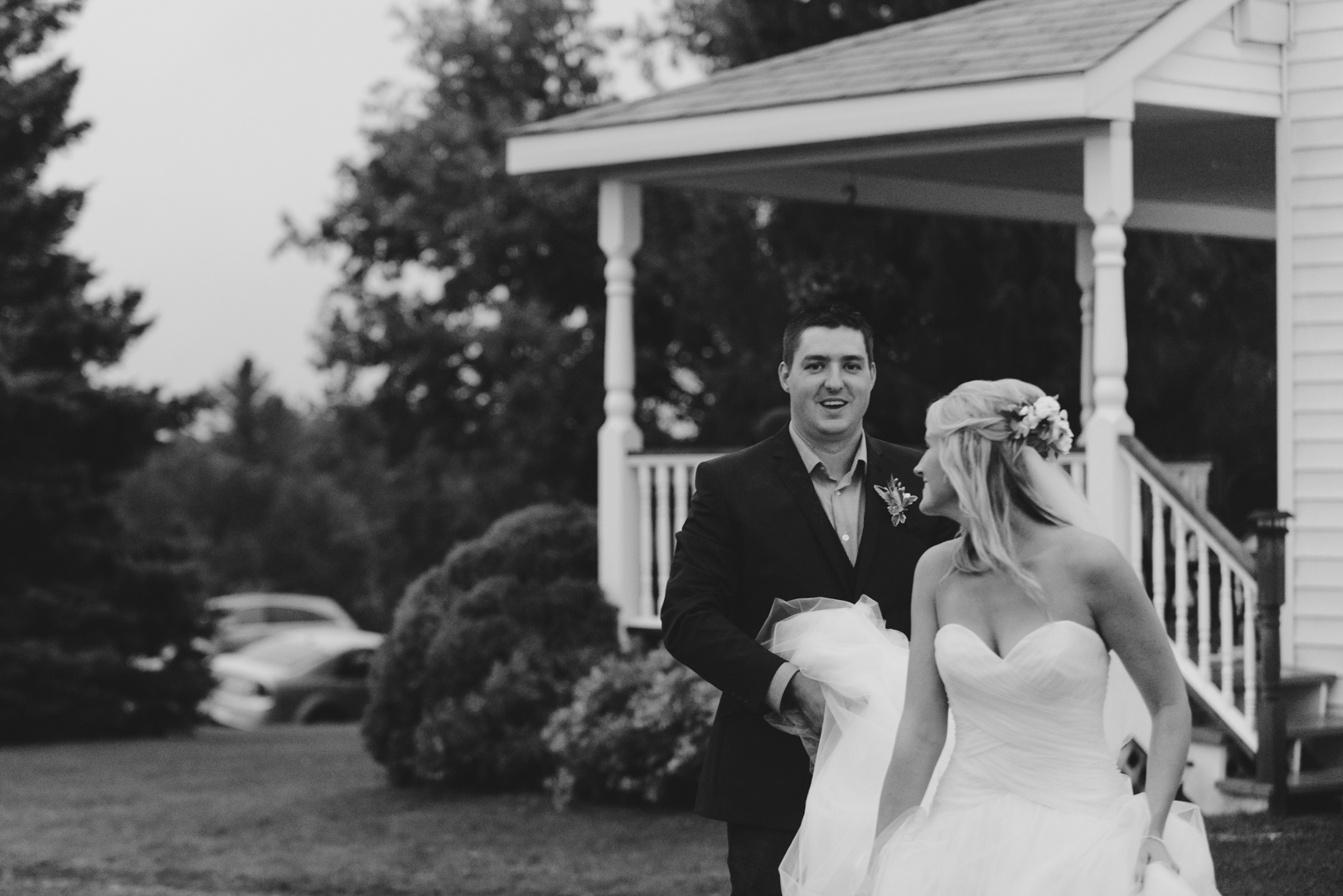 bride walking with her groom in front of farm house