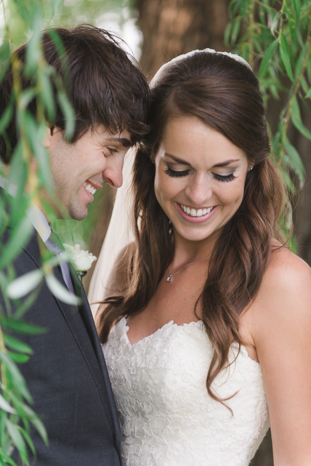 bride and groom standing in the leaves of a willow tree
