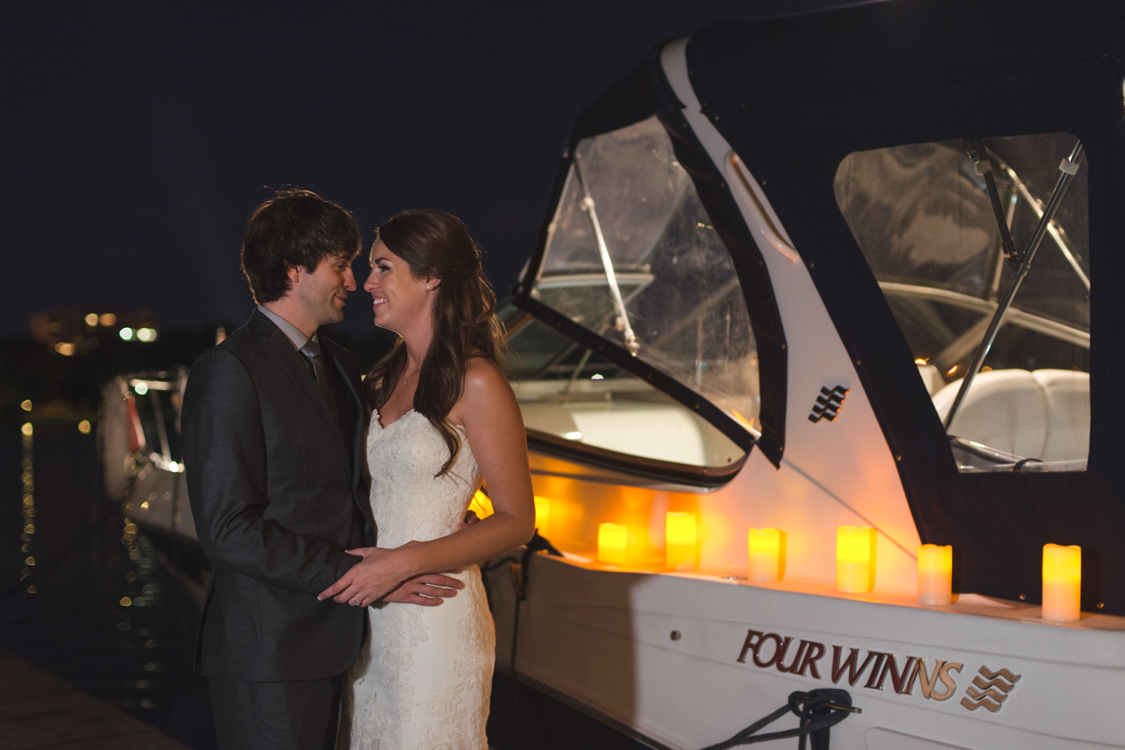 bride and groom standing next to boat at dow's lake at night