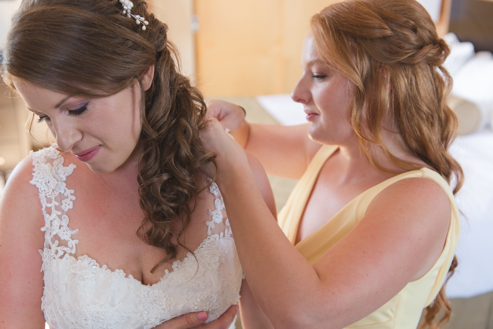 maid of honor helping the bride into her dress