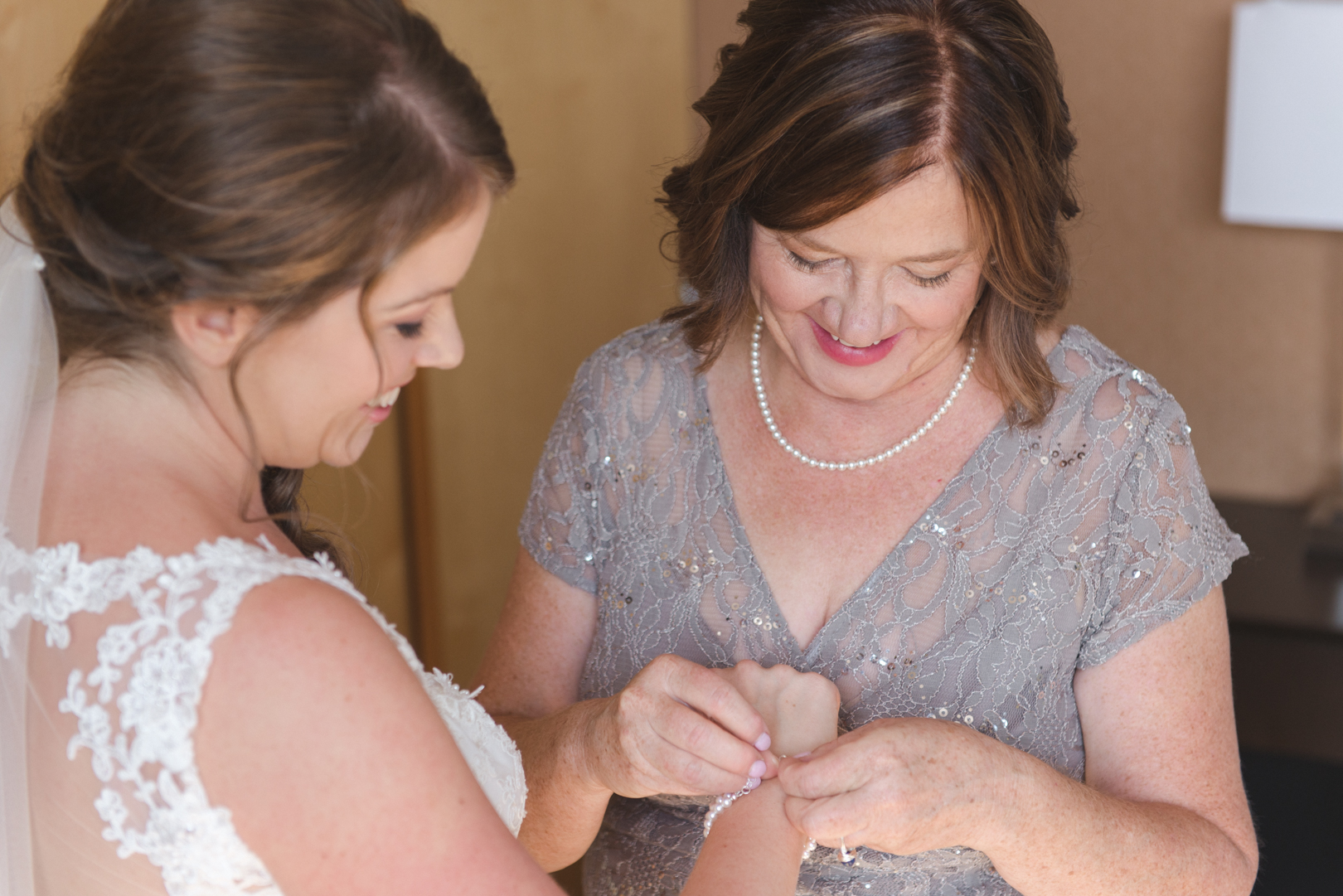 mother of the bride tying the bride's bracelet