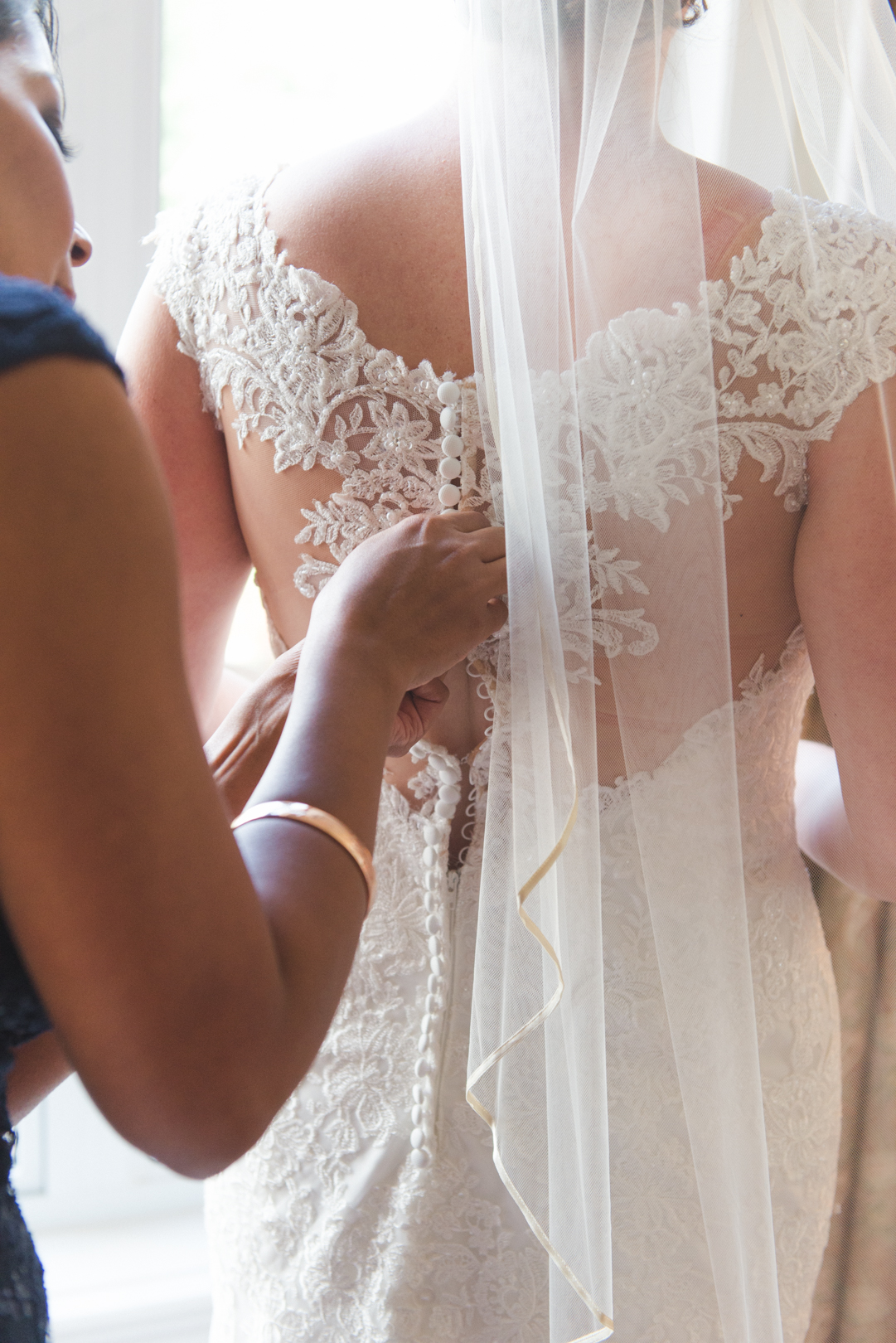 bridesmaid tying up wedding dress