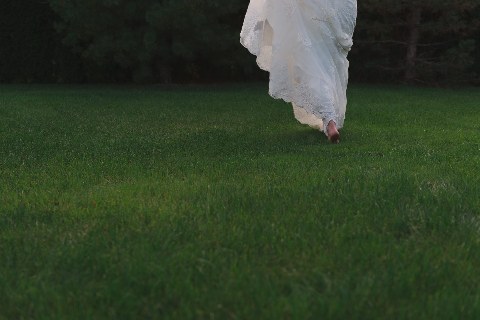 boho bride walking in the grass barefoot