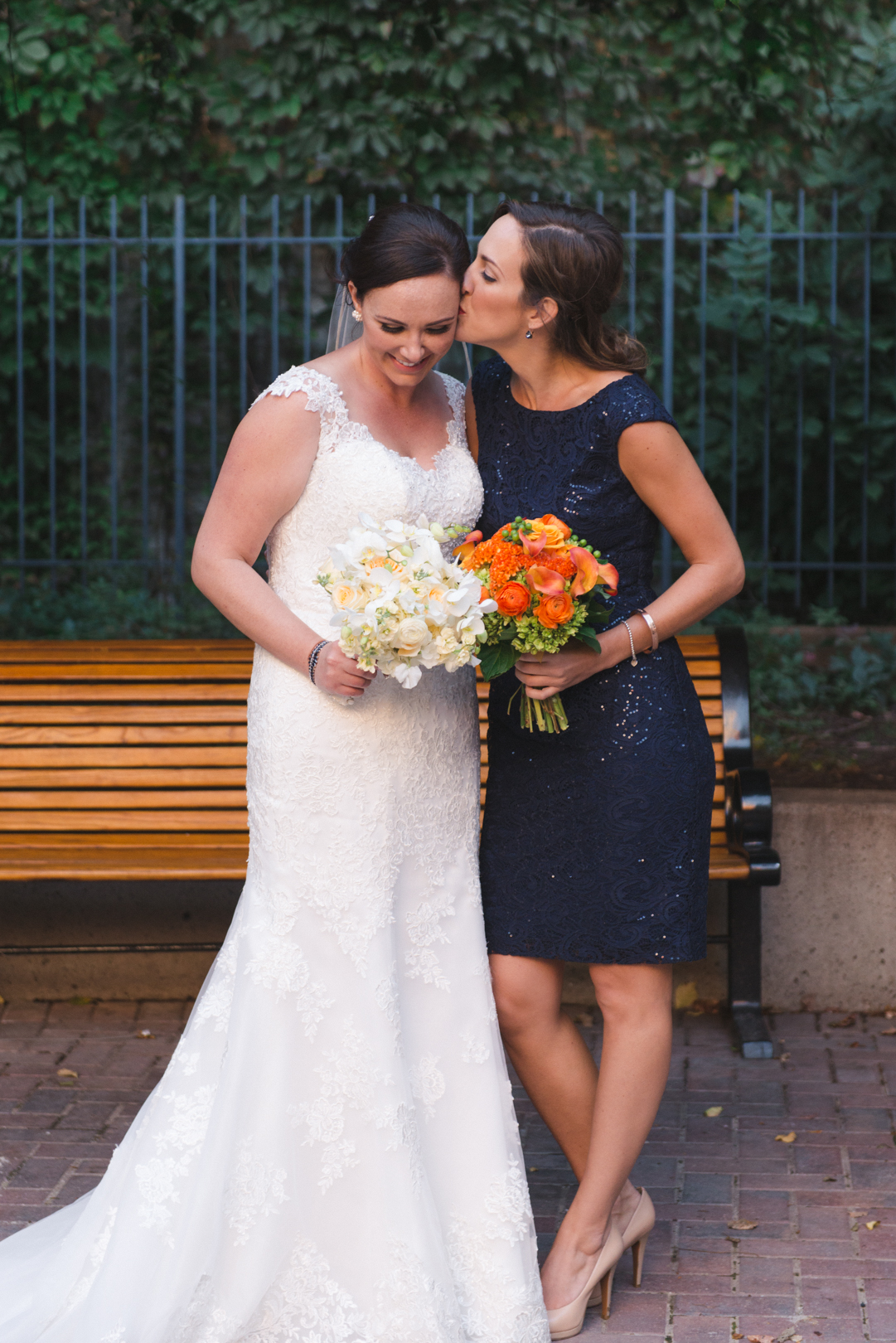 bridesmaid kissing bride in courtyard in byward market