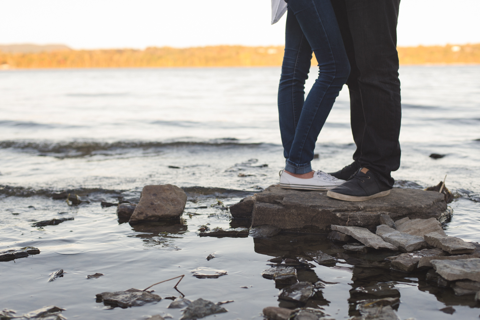 engaged couple standing on a rock on the ottawa river