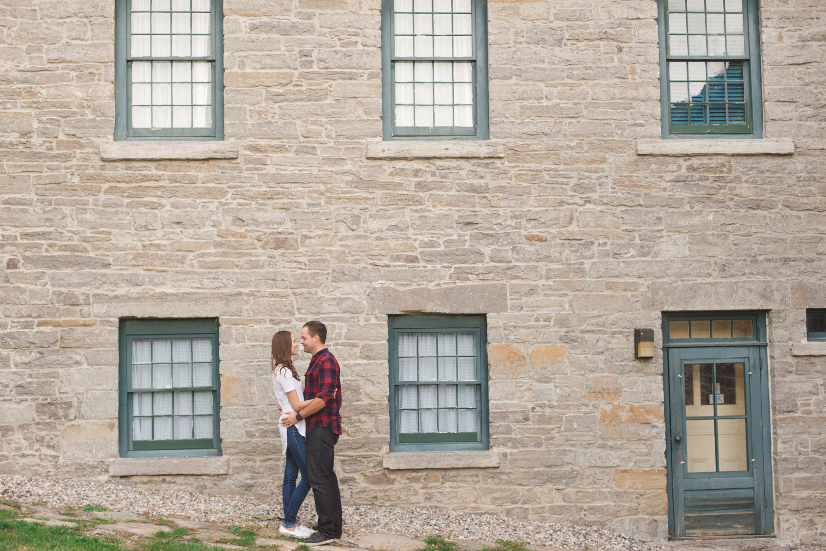 husband and wife to be in front of old stone house