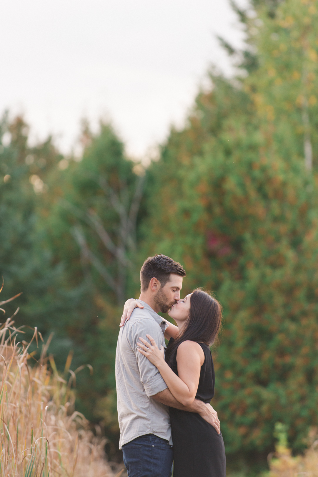 couple kissing with fall trees in the background