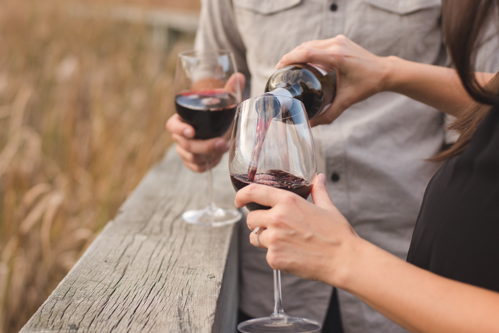 engaged couple pouring red wine outside