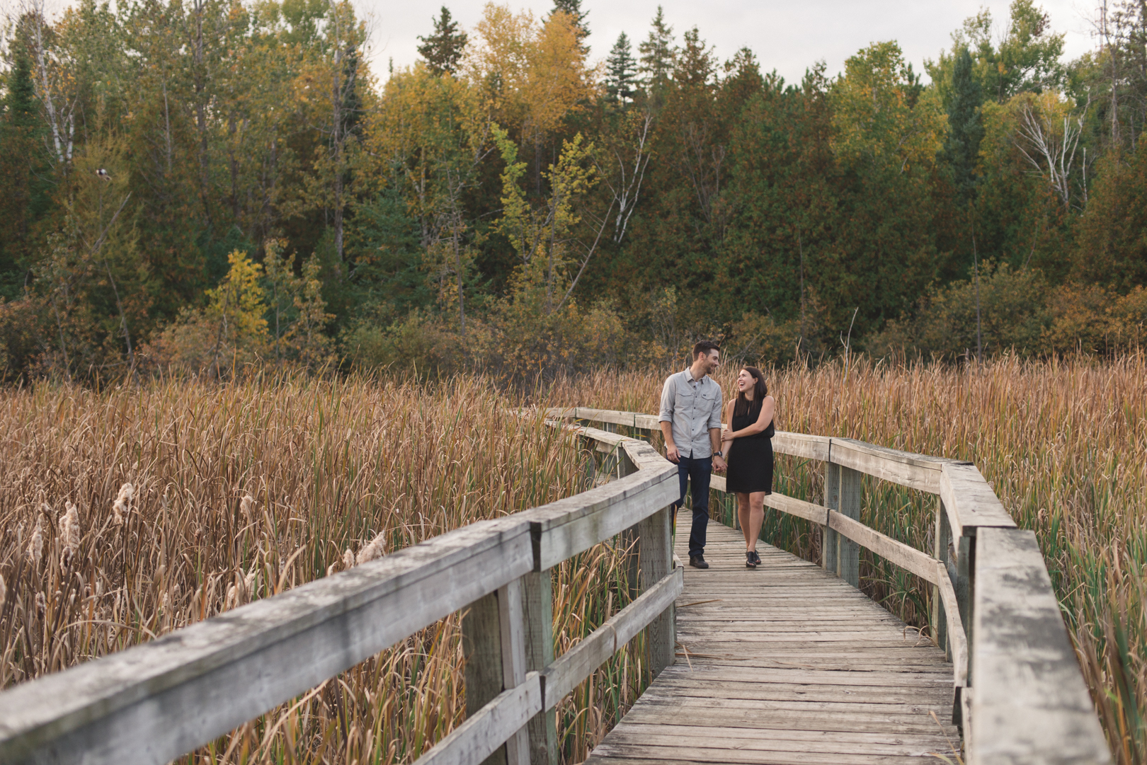 engaged couple walking down boardwalk of quarry trail