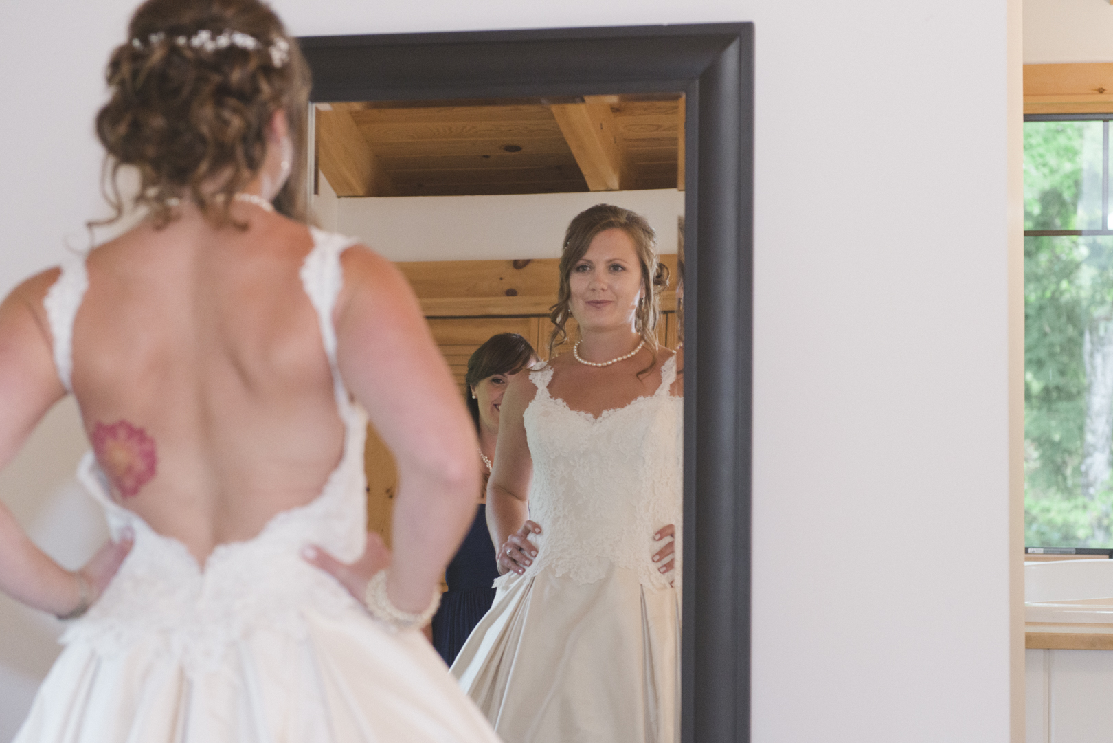bride putting on her dress in front of the mirror