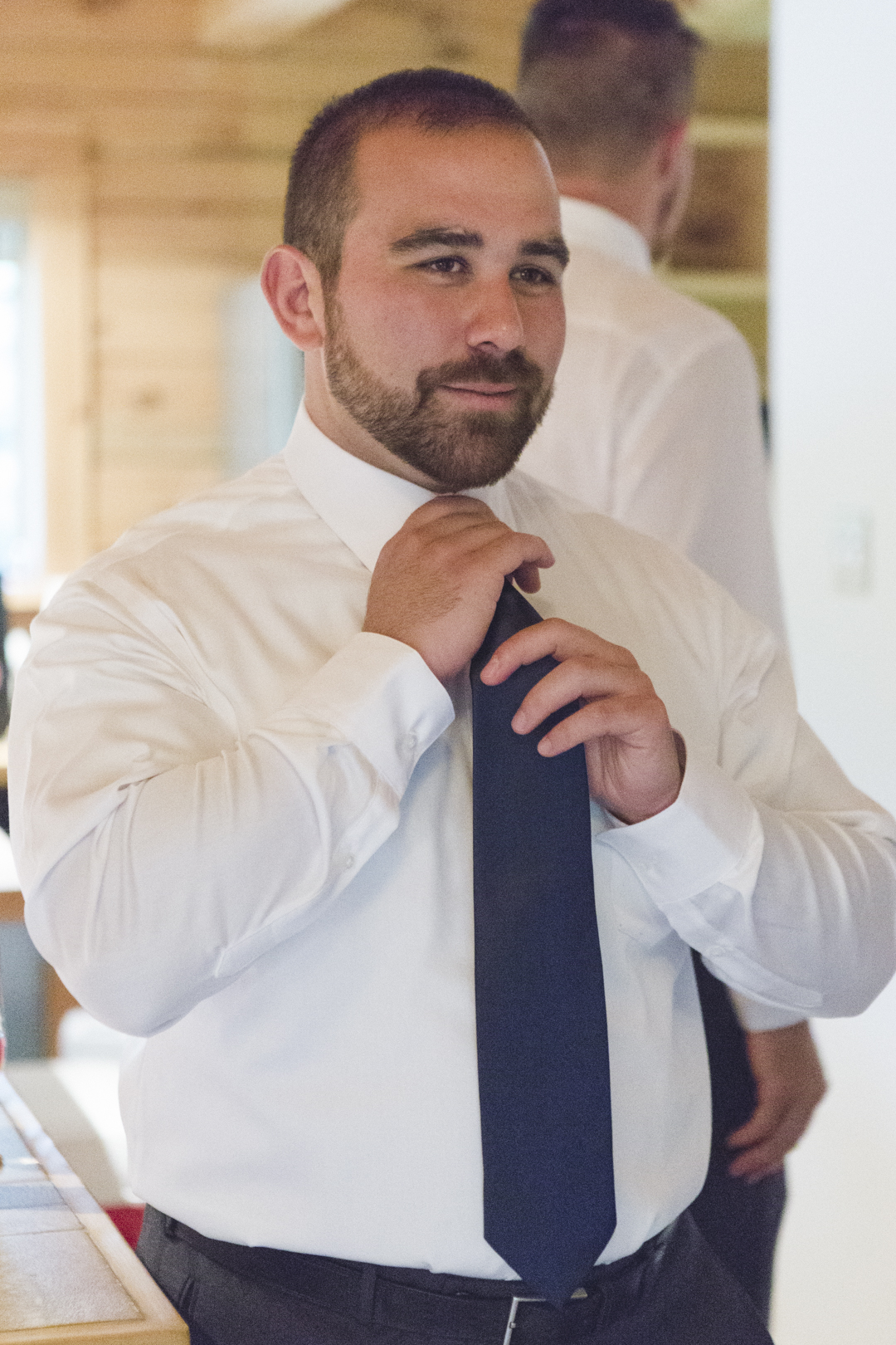 groom putting on navy blue tie