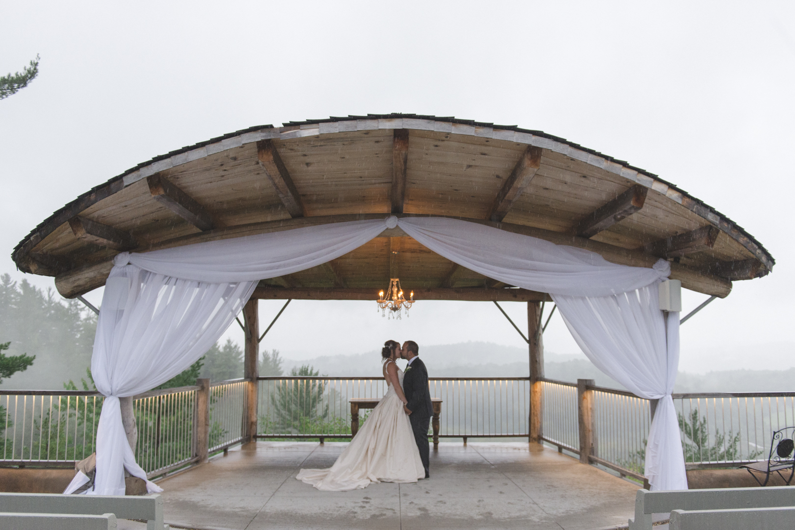 bride and groom kissing under gazebo at le belvedere in the rain
