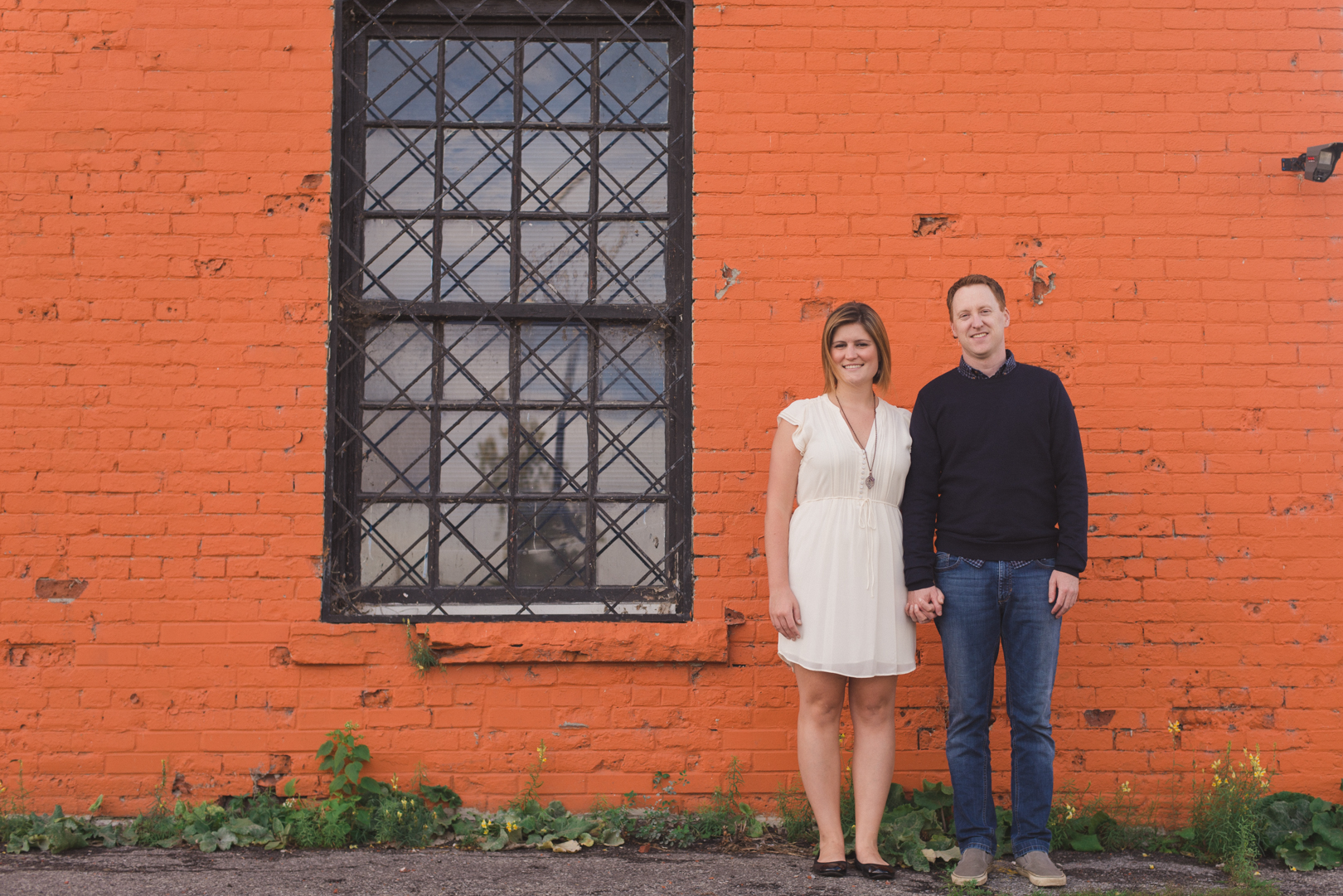 couple standing by orange brick wall