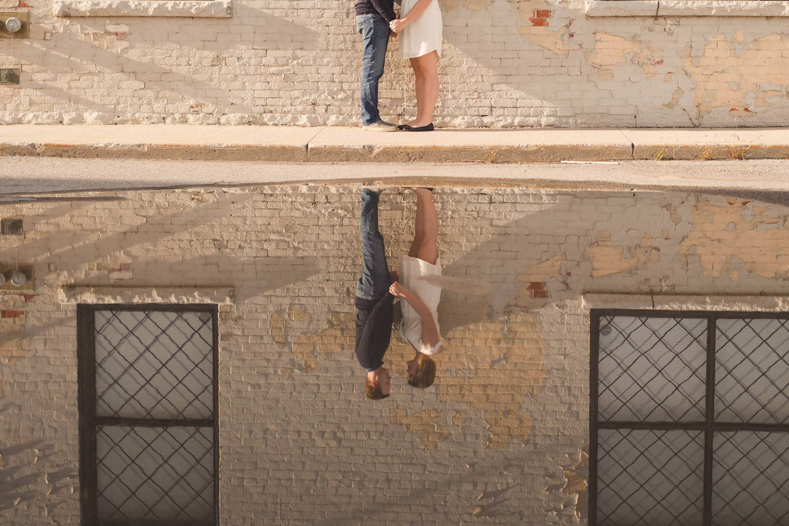 reflection of couple standing together against old brick building