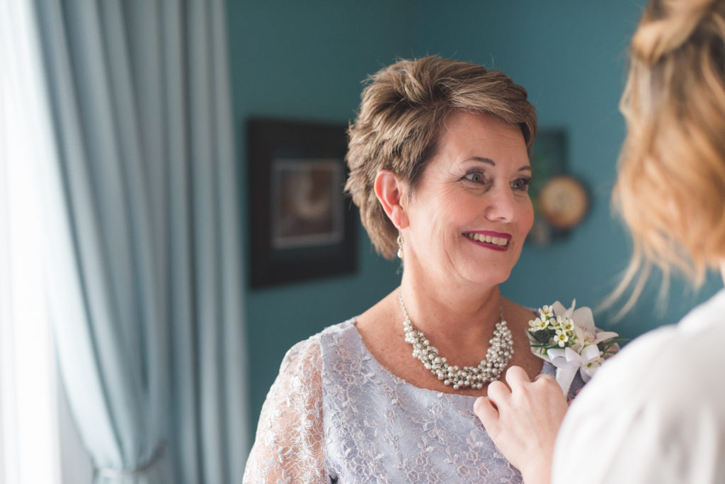bride putting on her mother's corsage