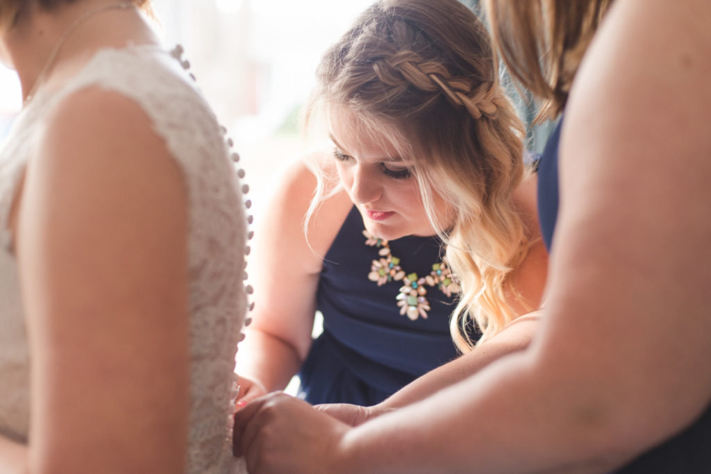 bridesmaids helping to tie up the bride's dress