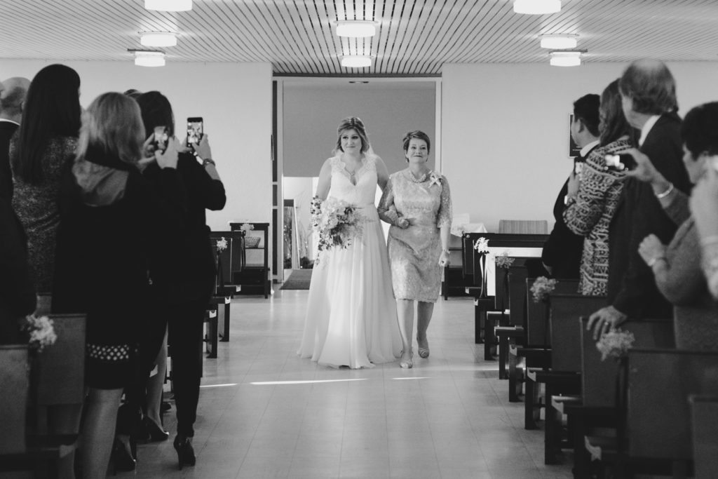 mother of the bride walking her daughter down the aisle at church wedding