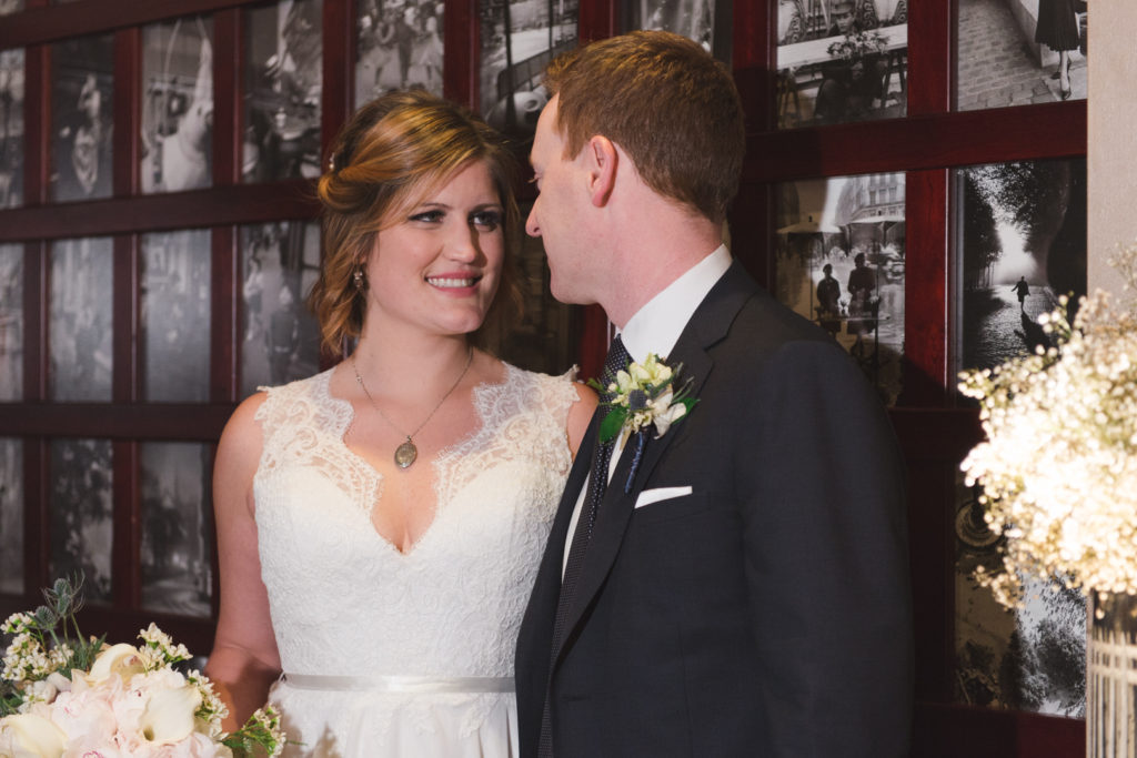 bride and groom against photo wall at luxe bistro