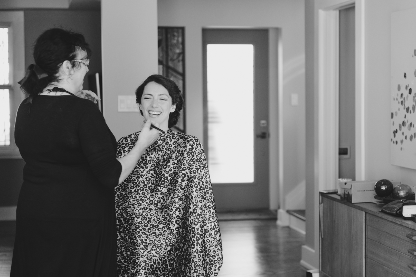 bride wearing leopard print cape while having her makeup done at home