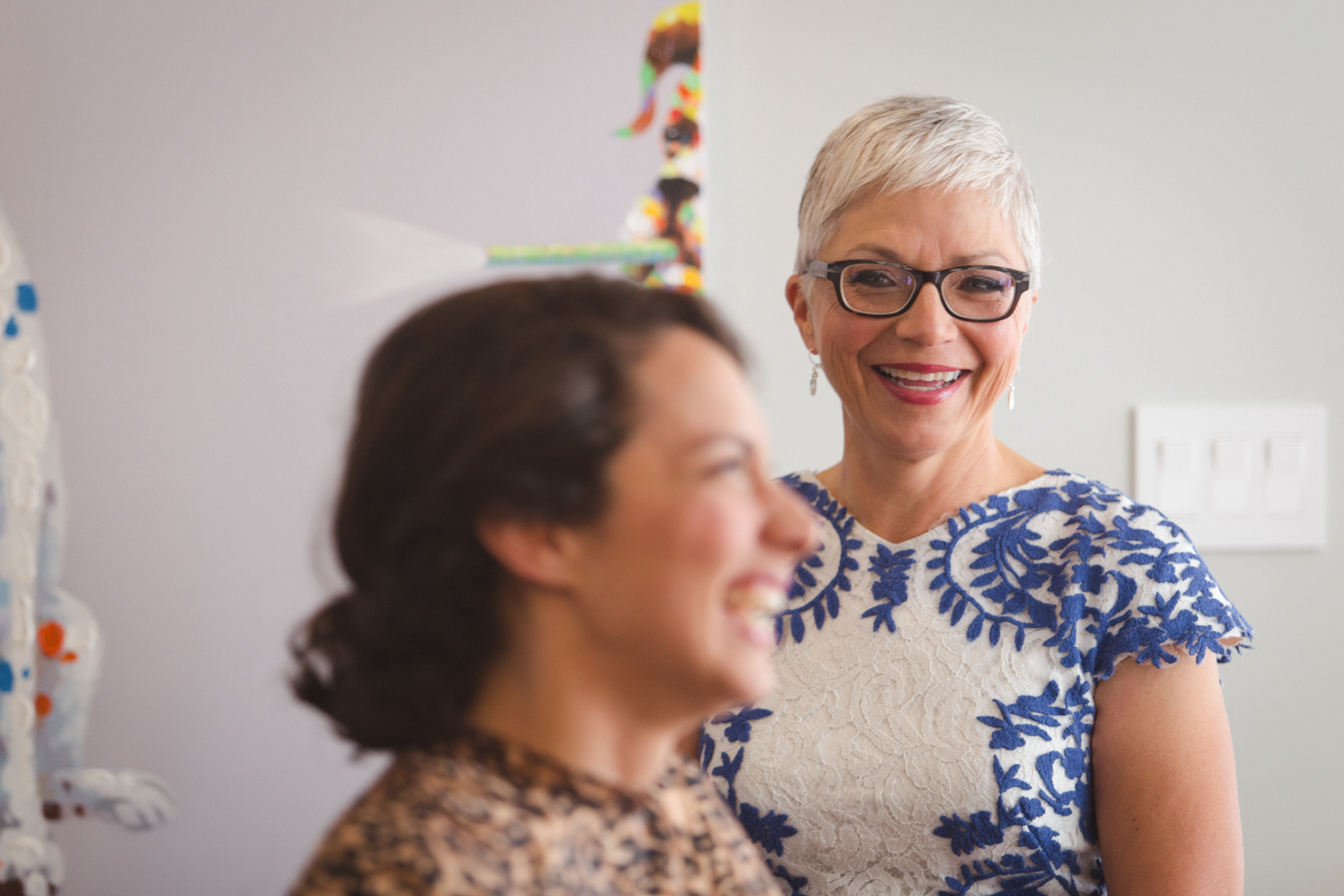 bride's mother smiling while bride has her makeup done