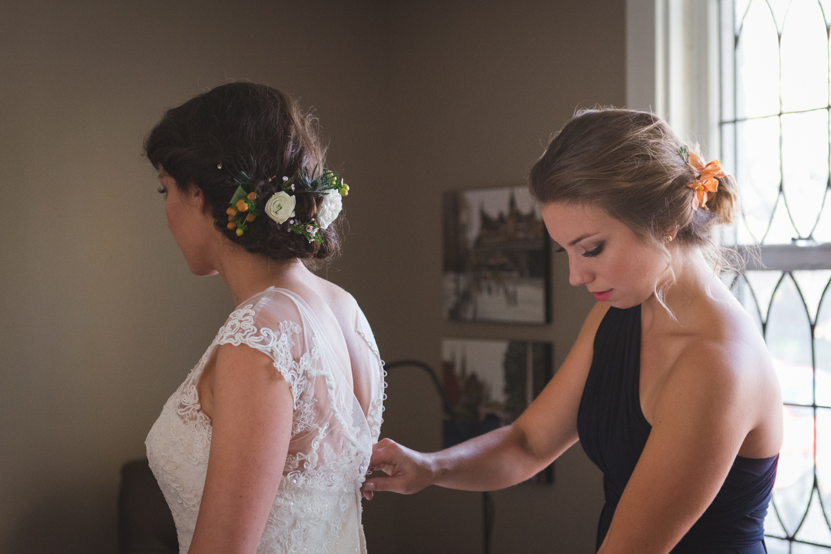 maid of honor tying up bride's dress