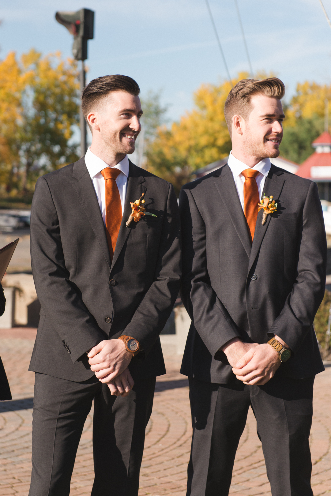 Groom and best man smiling as the bride walks down the aisle