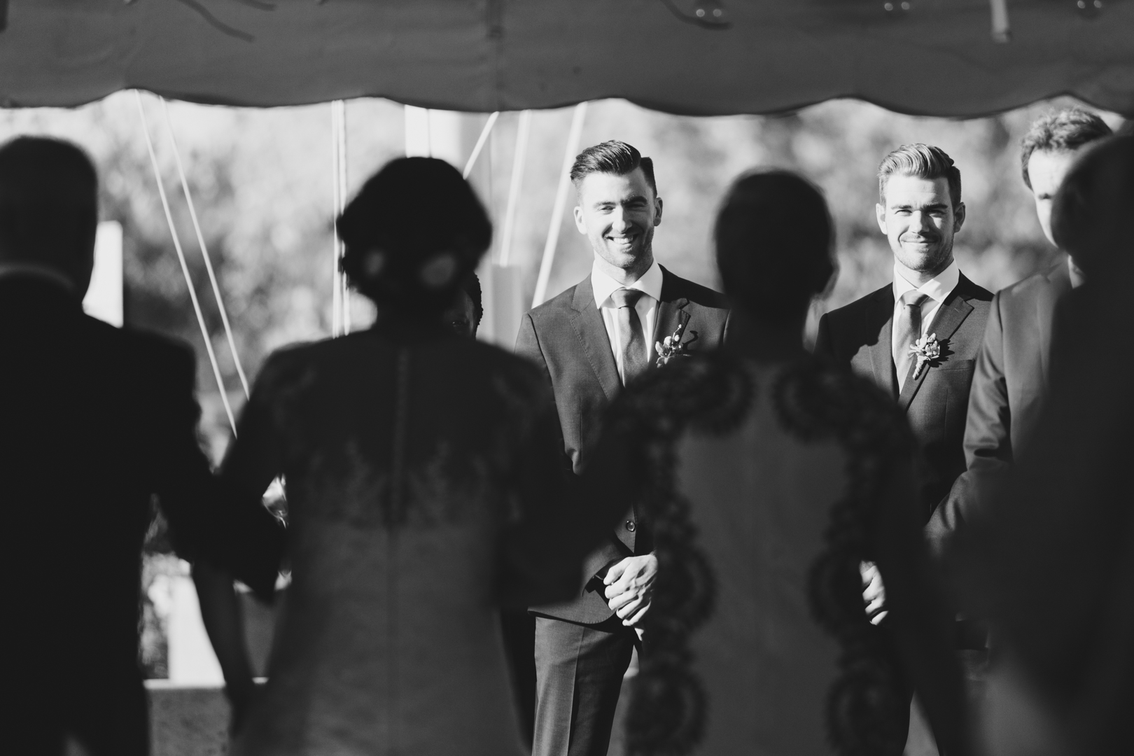 Groom smiling at his bride walking down the aisle