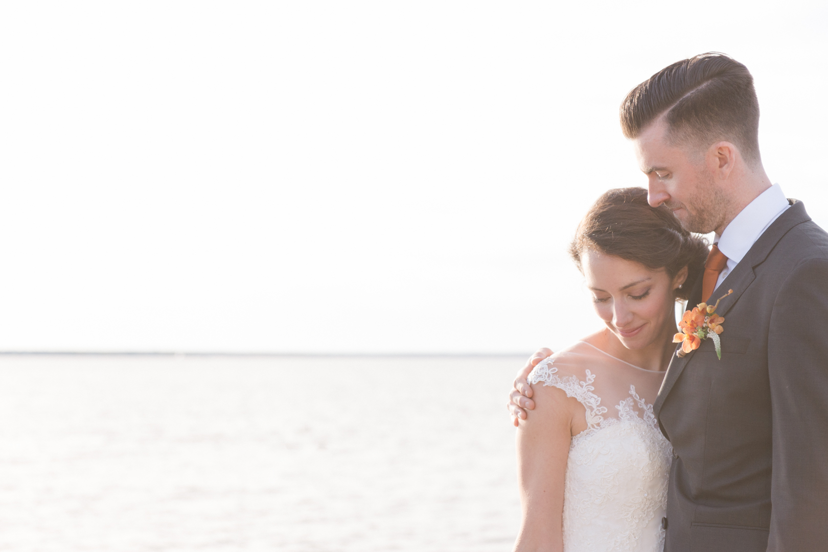 bride and groom standing at water's edge