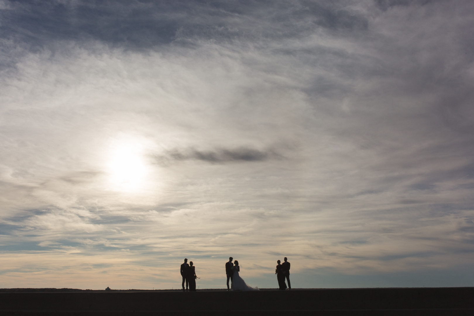 Silhouette of wedding party standing on pier at Britannia Yacht Club at sunset