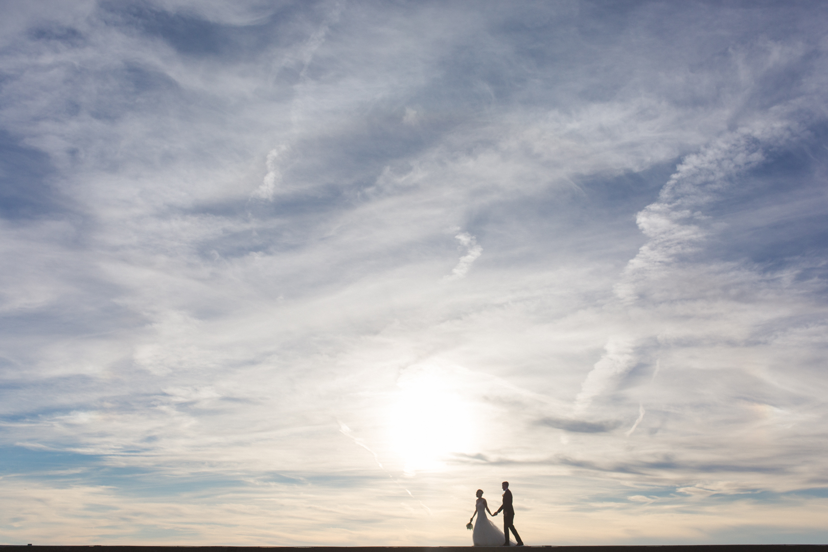 silhouette of bride and groom at sunset on pier at britannia yacht club