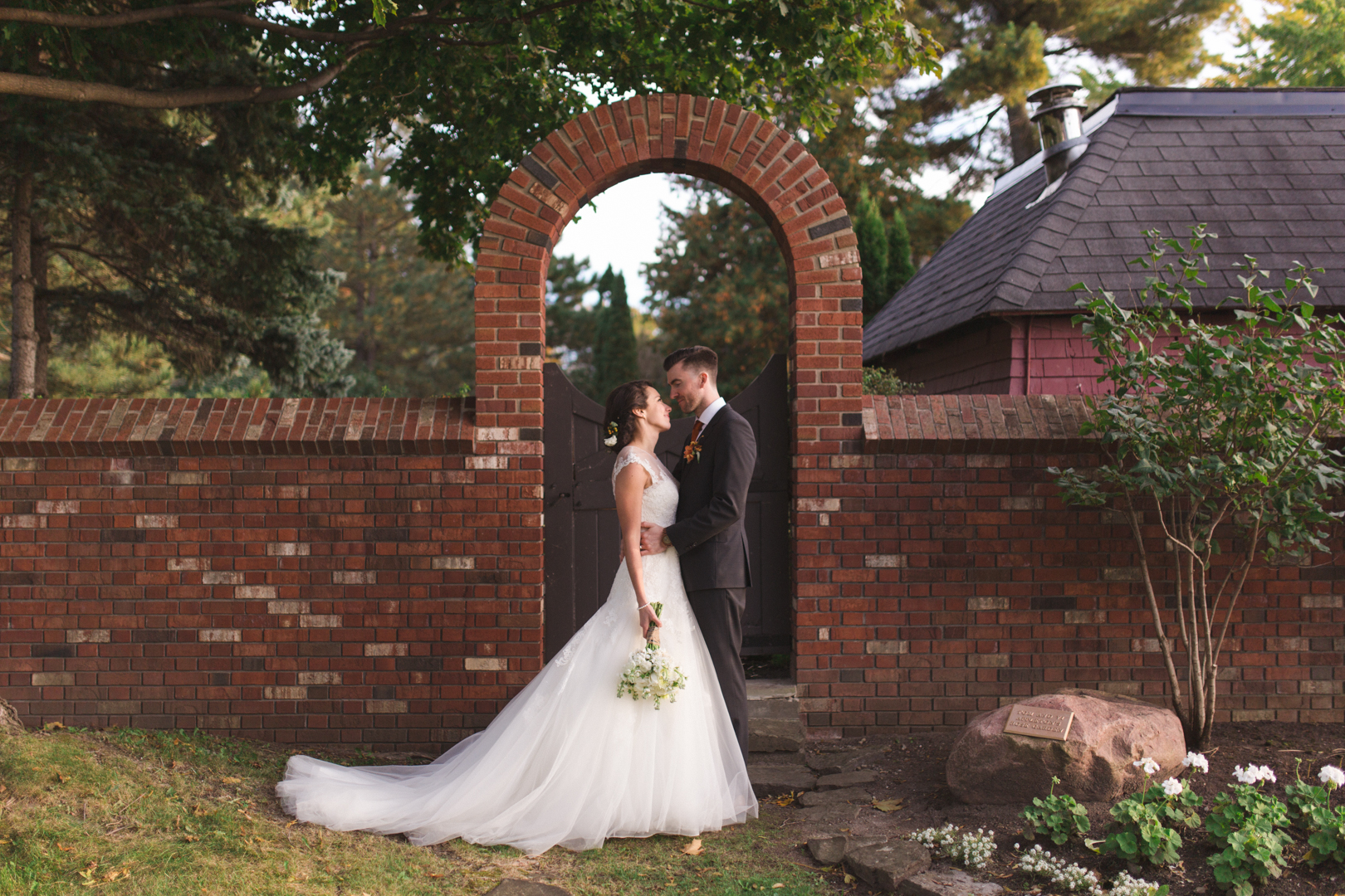 bride and groom kissing under brick archway