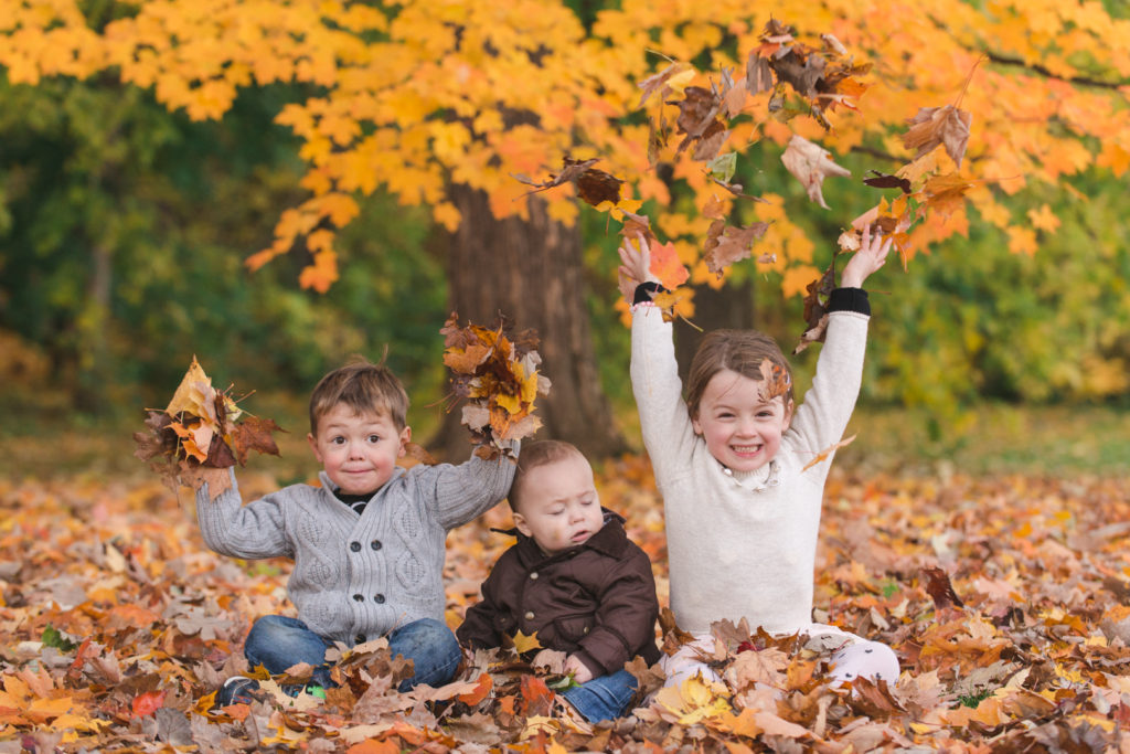 kids throwing fall leaves up in the air at the arboretum