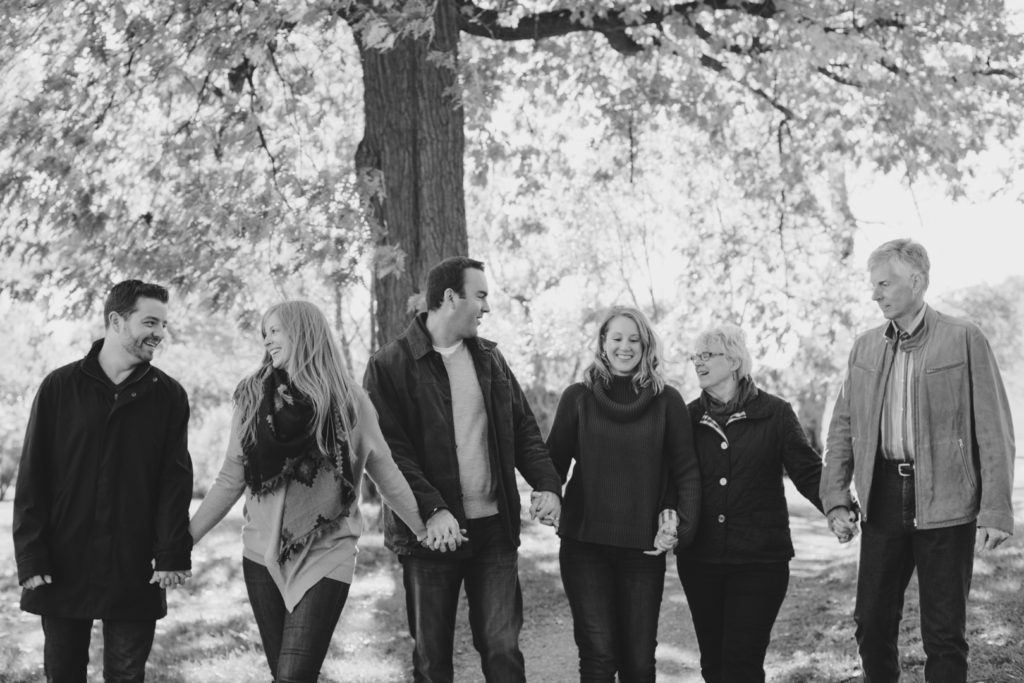 family walking hand in hand and laughing in black and white