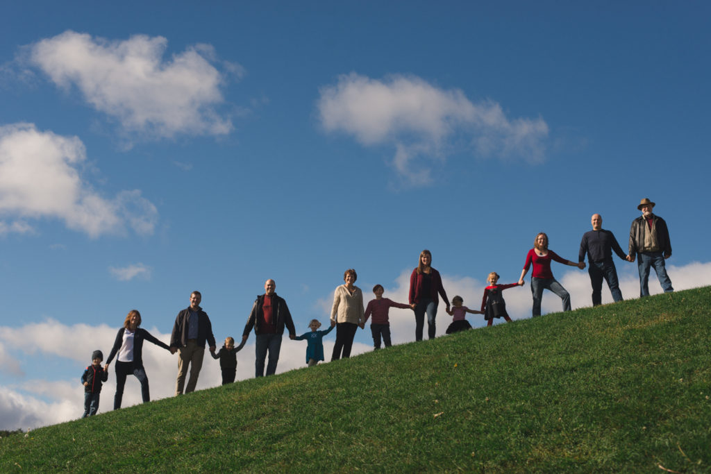 silhouette of extended family standing on a hill on a sunny fall day